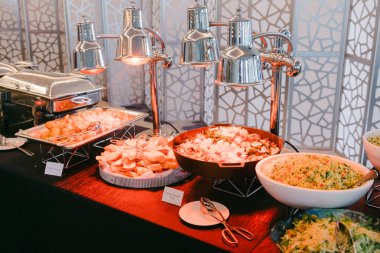Konuklar şenlikli bir toplantı sırasında şık bir büfede rengarenk yemek seçeneklerinin keyfini çıkarıyorlar..