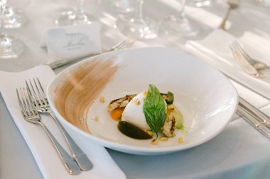 Güzel hazırlanmış ızgara balık, taze otlar ve beyaz bir tabakta renkli süsler..