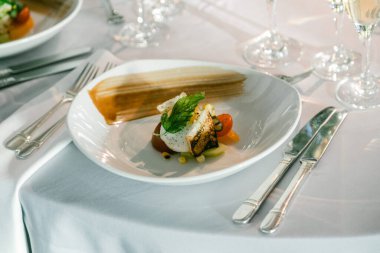 Taze bitkiler ve sebzelerle kaplanmış güzel bir gurme balık yemeği lüks bir yemek ortamında lokantaları bekliyor..