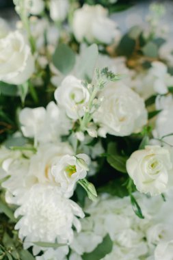 Narin beyaz güller, lisianthus ve yeşillik bahar kutlamaları için mükemmel, huzurlu bir çiçek dekoru oluşturur..