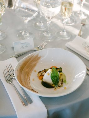 Izgara sebze, sos ve süslerle sunulmuş güzel bir yemek şık bir yemek masasında oturur..