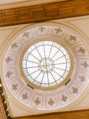 Parlak boyalı cam kubbe, karmaşık tasarım ve işçilikle tarihi bir binanın içini aydınlatır..