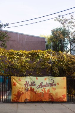 Çitin üzerindeki canlı bir sonbahar bayrağı yerel halkı mevsimi sıcak renkler ve motiflerle kutlamaya davet ediyor..