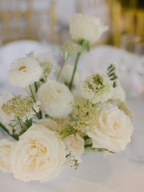 Beyaz çiçeklerin ve yeşilliklerin zarif bir şekilde düzenlenmesi şenlikli bir yemek ortamının zarif atmosferini arttırır..