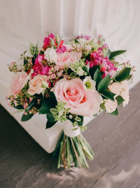 Pembe güller ve renkli çiçekler içeren bir buket zarif bir şekilde sergilenir, etkinlikler ve dekorasyonlar için mükemmeldir..