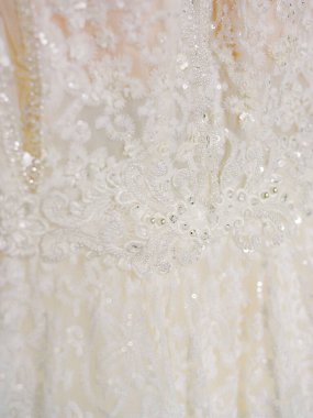 Karmaşık dantelli ve pırıl pırıl boncuklu bir gelinliğin yakın çekimi, zarif işçiliğin altını çizmek.