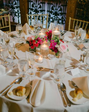 Şık bir mekanda zarif bir etkinlik için hazırlanmış mumlar ve taze çiçekler içeren güzel bir yemek masası..