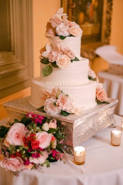 Mumlar ve romantik bir ortamda bir buket çiçekli çarpıcı bir düğün pastası..