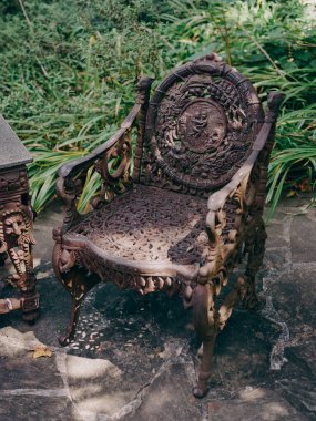 Güzel bir süslemeli sandalye, karmaşık tasarımlarla süslenmiş ve yumuşak güneş ışığıyla yıkanmış bir bahçede sessizce oturur..