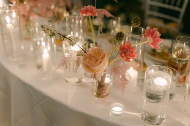 Yumuşak çiçek ve mumlarla süslenmiş çiçek dekoru akşam kutlaması için davetkar bir ortam yaratır..