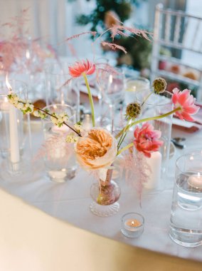 Yemek masasında güzel bir çiçek aranjmanı mumlarla özel bir kutlama için romantik bir ortam hazırlar..