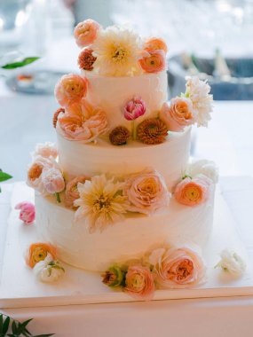 Göz kamaştırıcı bir düğün pastası, canlı çiçeklerle süslenmiş, neşeli bir kutlamada zarif bir şekilde sergilenmiş..