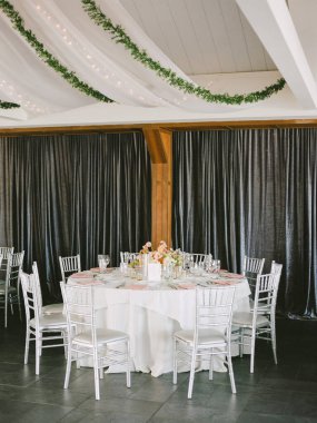 Gümüş sandalyeler ve çiçek süslemeleriyle güzel düzenlenmiş bir yemek salonu. Kutlama için hazır..