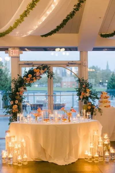 Süslü bir resepsiyon alanında çiçek aranjmanları, mum ışığında masalar ve alacakaranlıkta büyüleyici bir manzara vardır..