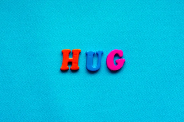 text hug rom plastic colored letters on blue paper background