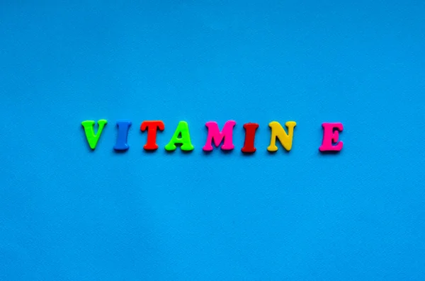 text vitamin e from plastic colored letters on blue paper background