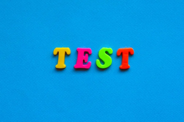 text test from plastic colored letters on blue paper background