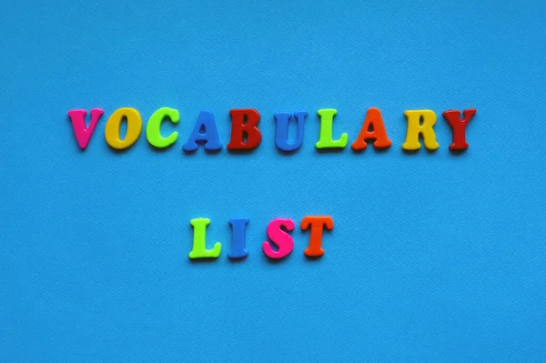 text vocabulary list from plastic colored letters on blue paper background