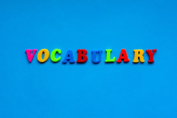 text vocabulary from plastic colored letters on blue paper background
