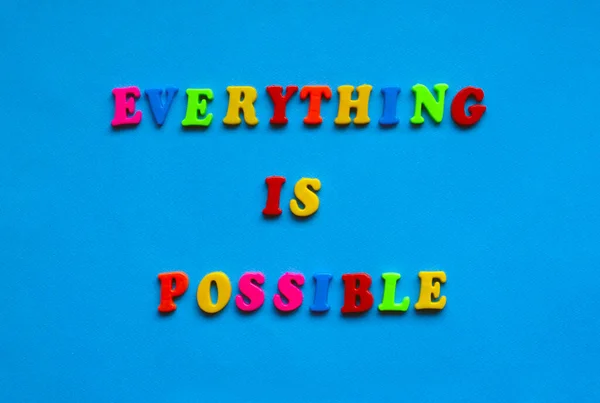 text everything is possible from plastic colored letters on blue paper background
