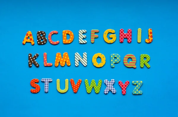 alphabet  from bright colored paper letters on blue paper background