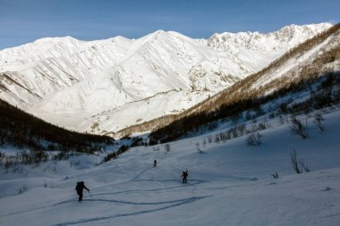 Serbest kayakçılardan oluşan bir ekip Kafkasya Dağları, Svaneti, Gürcistan, kırsal kesimdeki karlı sırtlara tırmanıyor.