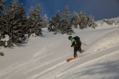 Snowboard 'cu eğildi ve frenler serbest yamaçta derin kar püskürtüyor. Taze kar altında kayak yaparak yokuş aşağı. Havada kar kıvrımları