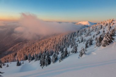 Güzel kış günbatımı rüzgarlı turuncu bulutlu dağların üzerinde Marmarosy, Karpatya dağları