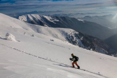 Kayak turistleri kırsal bir arazide karla kaplı bir dağın tepesine tırmanır. Adrenalin dolu kış maceraları.