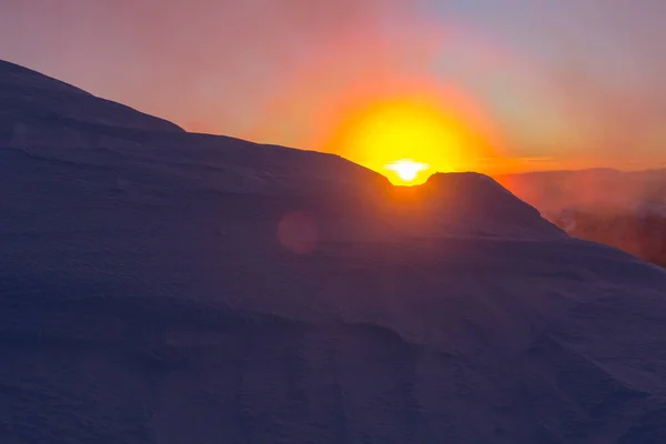 Bright orange sunrise of the sun disk in the snowy mountains. Marmarosy, The Carpathian mountain range