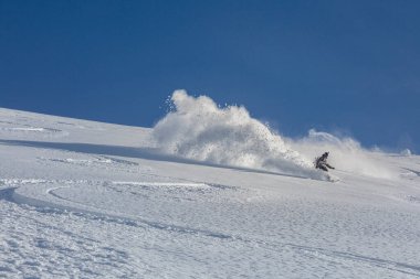 Serbest çalışan bir snowboardcu derin karda yokuş aşağı gidiyor. Adrenalin açık hava kış maceraları