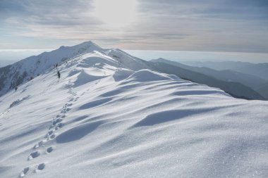 Alp dağları beyaz kar ve dramatik bulutlu gökyüzü ile kaplı. Doğada günbatımı kışı. Sıcak güneş ışığı altında soğuk ağaçlar