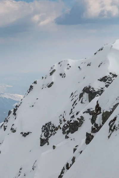 一名自由滑雪者从岩石间陡峭的山坡上滑落 那是一次令人兴奋不已的户外探险 — 图库照片