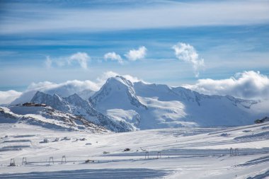 Avusturya Alpleri 'ndeki bir dağ kayak merkezinin tepesinde karla kaplı büyük kayalık bir dağ, Tyrol, Avusturya
