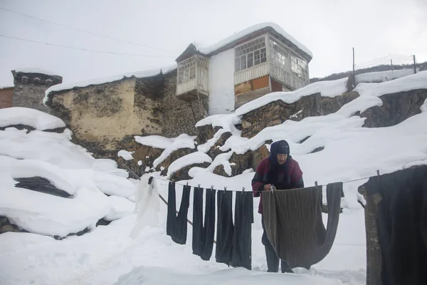 Ushguli, Svaneti - 1 Feb, 2020: An old woman hangs clothes in the Georgian village