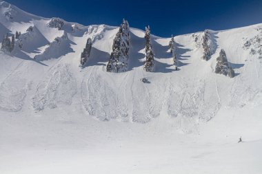 Avalanches descend among the rocks in the mountains, winter freeride extreme