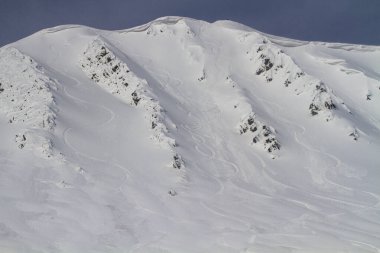 Freeride downhill on a steep and snowy slope next to a snow cornice in the high mountains, winter freeride extreme sport.