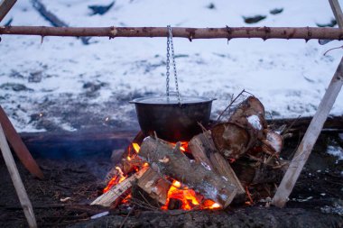 food is prepared in a cauldron on an open fire, rest in the evening in nature