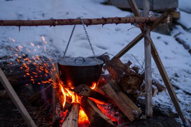 food is prepared in a cauldron on an open fire, rest in the evening in nature