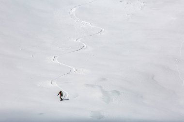 Taşra snowboardındaki beyaz tüylü kar yığınını incelikle oyar. Arkasında kış sporlarının güzelliğini yansıtan nefes kesici bir sahne bırakır..