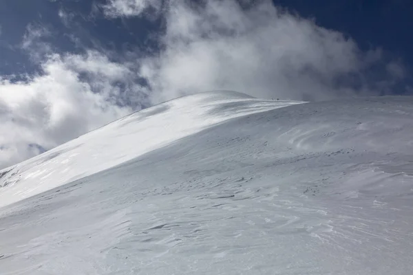 多云的天空为白雪覆盖的高山提供了令人震惊的背景 它们的山峰上覆盖着一层洁白的白雪 — 图库照片