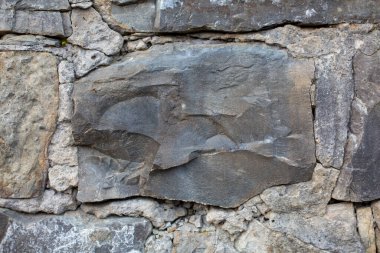 Büyük taş güvenli bir şekilde duvara gömülü, yapıya güç ve istikrar kazandırıyor.