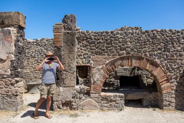 Bir adam antik Roma şehri Pompei 'deki harabelerde bir tuğla fırının fotoğrafını çekiyor.