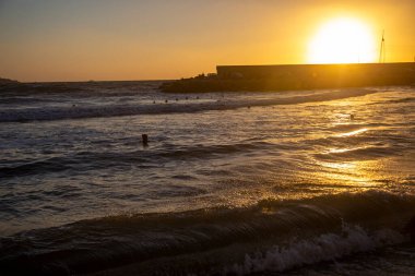 Okyanusun üzerinde bir gün batımı ve suda bir sörfçü. Tyrhenian Deniz Kıyısı