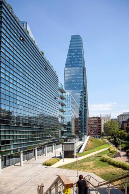 Modern bir binanın yeşil çatısı ve cam cephesi çevre şehri yansıtır. Milan, İtalya