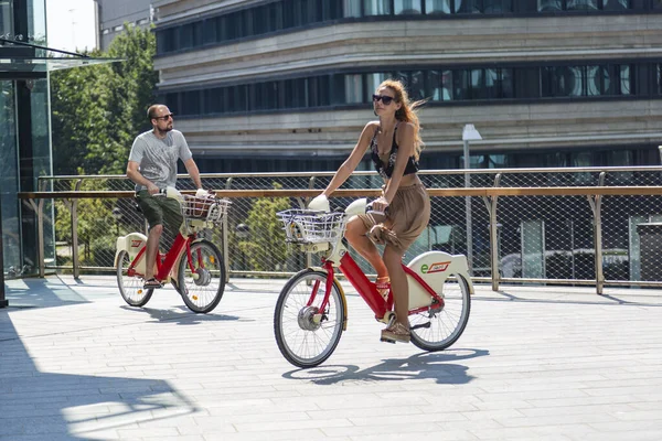 2022年8月11日 イタリア ミラノ オフィスビルを背に自転車に乗る2人 — ストック写真