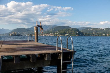 Arka planda dağlar ve göl manzaralı ahşap bir rıhtım. Orta Gölü, İtalya