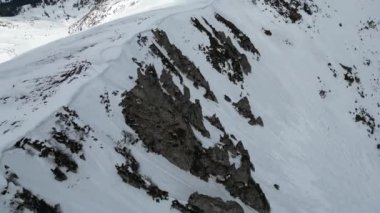 Arka planda bulutlu bir gökyüzü olan karlı kayalık bir dağ sırasının üst görüntüsü. Shpyci ve Hoverla, Karpat Dağları