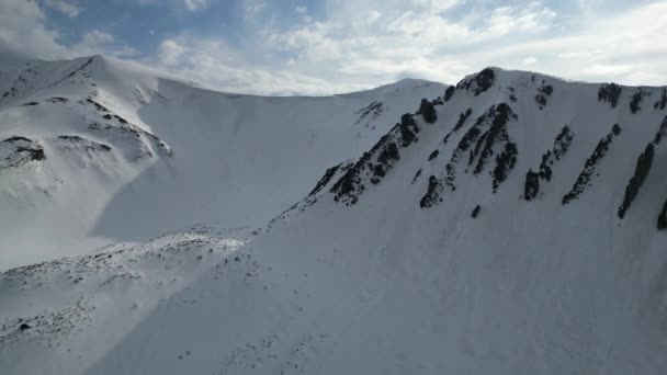 Arka Planda Bulutlu Bir Gökyüzü Olan Karlı Kayalık Bir Dağ — Stok video
