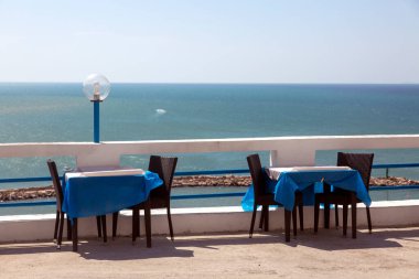 Deniz kıyısındaki restoranın masaları, deniz kıyısının manzarası.